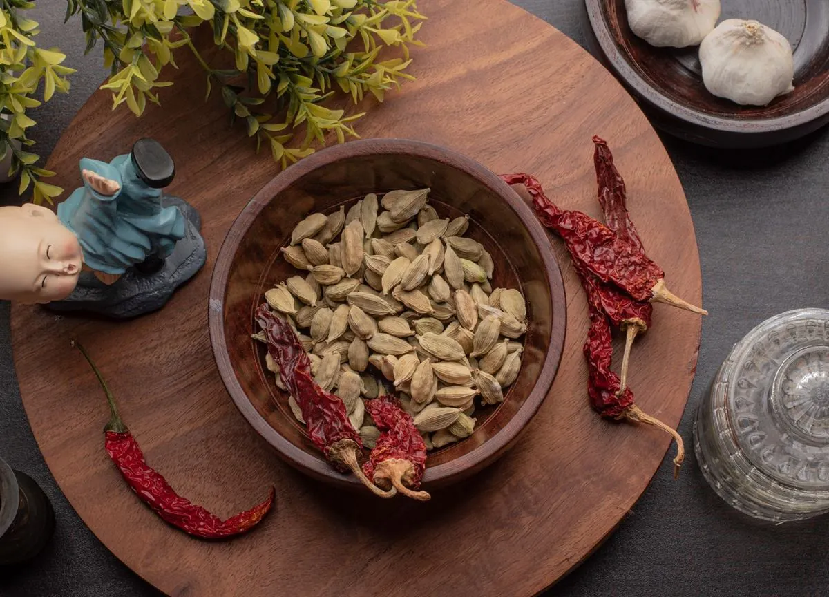 Bowl of green cardamom on a wooden board