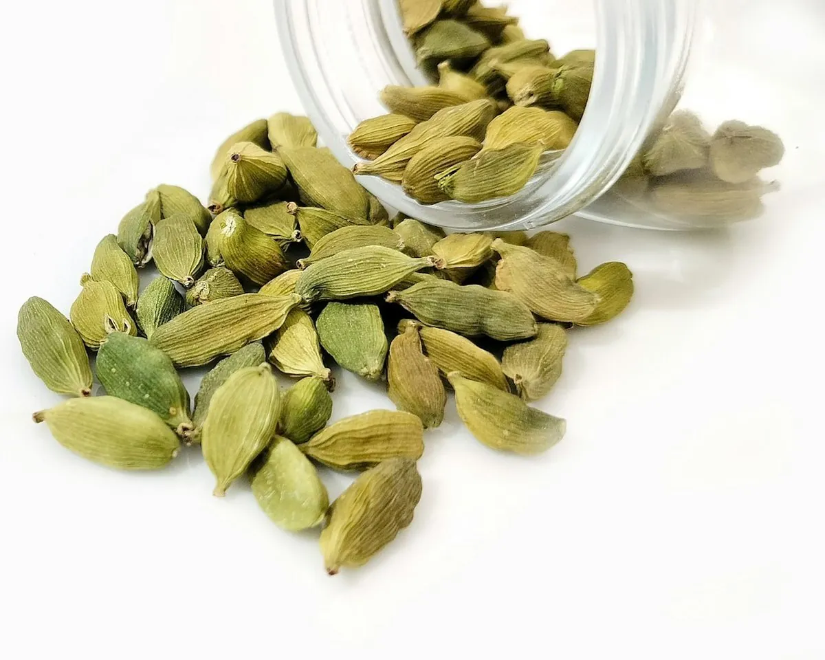 Glass jar tipped over with green cardamom spilling out